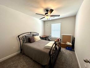 Greenville house for rent - A bedroom with a bed, a ceiling fan, and a window with blinds.