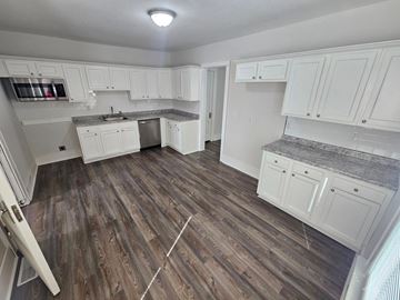 Lima apartment for rent - A kitchen with white cabinets and a wooden floor.