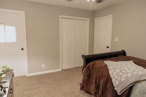 Clarksville house for rent - A bedroom with a bed, two doors, and a ceiling fan.
