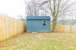 Clarksville house for rent - A small blue shed sits in a grassy area between two wooden fences.