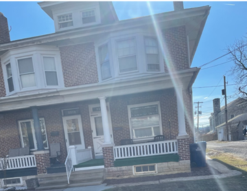 West Lawn apartment for rent - A two-story brick house with a white porch.