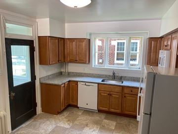 West Lawn house for rent - A kitchen with brown cabinets and a white fridge.