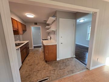Gary house for rent - A kitchen with brown cabinets and a white fridge.