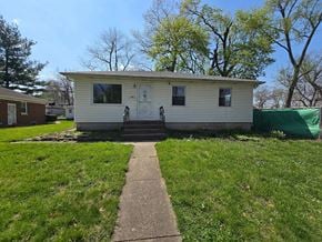 Gary house for rent - A small white house with a green tarp in the background.