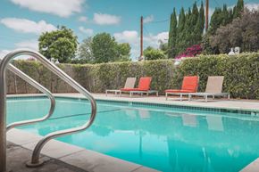 Van Nuys apartment for rent - A pool with a metal ladder and two red chairs.