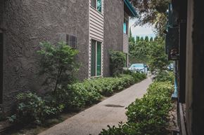 Van Nuys apartment for rent - A narrow alley with a building on the left and a car parked on the right.