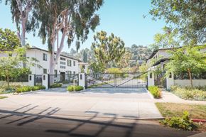Eagle Rock apartment for rent - A gated entrance to a residential area with trees and houses in the background.