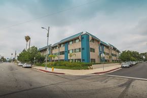 Van Nuys apartment for rent - A street view of a blue building with cars parked in front.