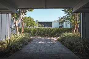 Studio City apartment for rent - A pathway leads to a building with a fence and trees on either side.