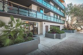Santa Monica apartment for rent - A modern building with a balcony and plants in front.