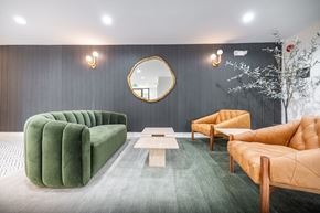 Pasadena apartment for rent - A modern living room with a green sofa, a wooden coffee table, and a round mirror on the wall.