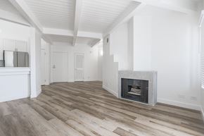 Reseda apartment for rent - A spacious room with a fireplace and wooden flooring.