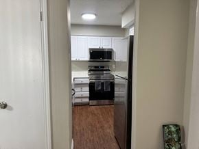 Irving house for rent - A kitchen with a black fridge and white cabinets.