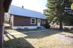 Whitefish apartment for rent - A small house with a metal roof and a tree in front.