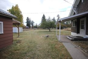 Whitefish apartment for rent - A house with a brown exterior and a white door is surrounded by a grassy area.