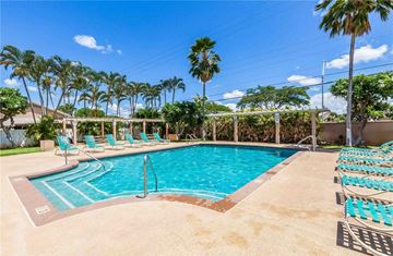 Ewa Beach apartment for rent - A pool surrounded by palm trees and lounge chairs.