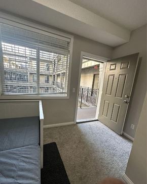 Calgary apartment for rent - A bedroom with a bed, carpet, and a door leading to a balcony.