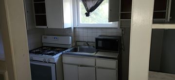 Bedford apartment for rent - A small kitchen with a white oven and a microwave above a sink.