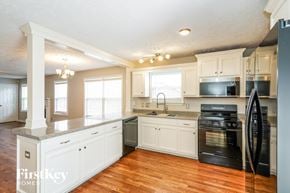 Antioch house for rent - A kitchen with white cabinets and a black fridge.