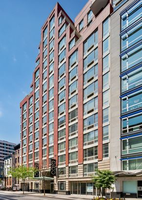 New York apartment for rent - A tall red building with many windows is the main focus of the image.