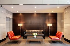 New York apartment for rent - A modern living room with a black couch, two red chairs, and a coffee table.
