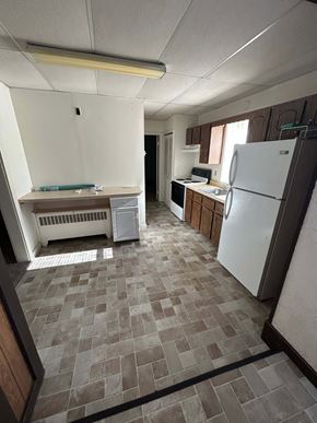 Laurys Station apartment for rent - A kitchen with a white fridge and brown tiled floor.