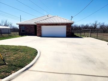 San Angelo house for rent - A garage with a metal roof and a white door is surrounded by a concrete driveway.