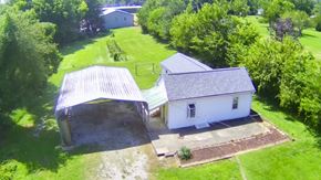 New Albany house for rent - A white house with a grey roof is surrounded by a green lawn.