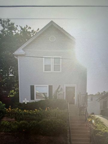 Kansas City apartment for rent - A house with a grey siding and a white door is surrounded by greenery.