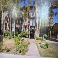 Toluca Lake apartment for rent - A sunny day in a courtyard with a pathway, greenery, and a building in the background.
