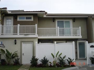 Newport Beach apartment for rent - A two-story house with a white fence and a small front yard.