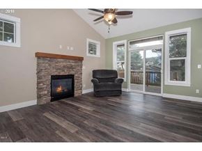Lincoln City house for rent - A living room with a fireplace and a ceiling fan.