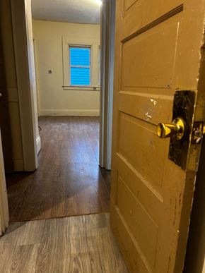 Syracuse apartment for rent - A room with a wooden floor and a door with a gold handle.