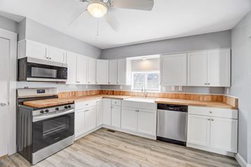 Lima house for rent - A kitchen with white cabinets and a wooden countertop.