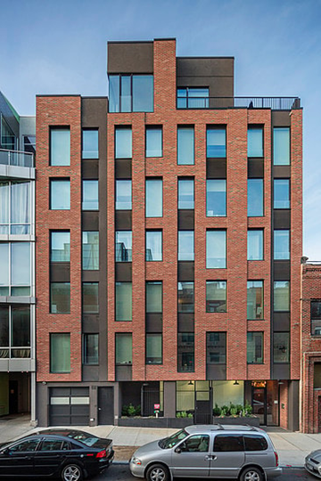 Brooklyn apartment for rent - A red brick building with a black car parked in front.