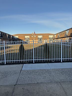 Bayonne apartment for rent - A white fence in front of a building with a flag on it.