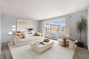 Bayonne apartment for rent - A modern living room with a white sofa, a coffee table, and a large window.