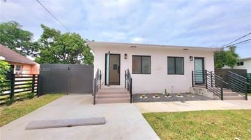 Miami apartment for rent - A house with a grey door and windows is surrounded by a black fence.