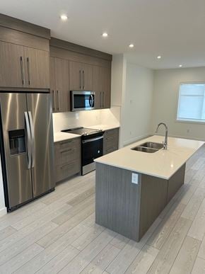 Calgary house for rent - A modern kitchen with a stainless steel refrigerator and a white countertop.