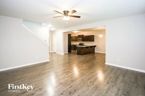Statesville house for rent - A spacious room with a wooden floor and a ceiling fan.