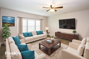 Statesville house for rent - A living room with a white couch, a coffee table, a flat screen TV, and a ceiling fan.
