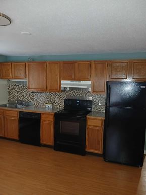 North Providence apartment for rent - A black refrigerator is in a kitchen with wooden cabinets.