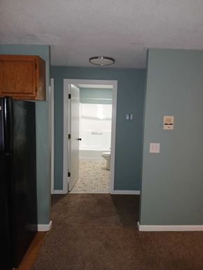 North Providence apartment for rent - A kitchen with a black fridge and a doorway leading to a bathroom.