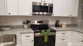 Greenville house for rent - A kitchen with a stove top oven and microwave above it.