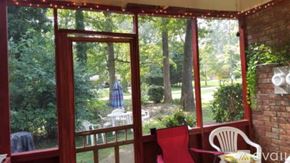 Atlanta apartment for rent - A red chair is in front of a window with a view of a lawn and trees.