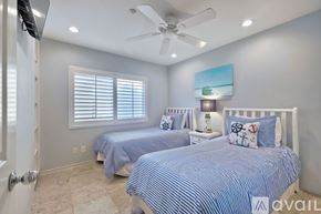 Oceanside apartment for rent - A bedroom with two beds and a ceiling fan.