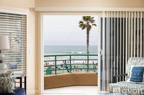 Oceanside apartment for rent - A view of a beach from a room with a chair and a table.
