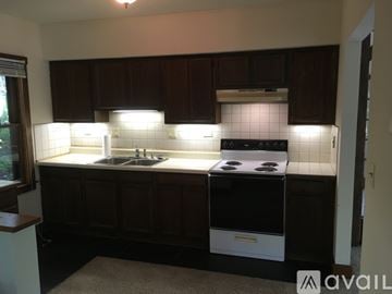 Cary house for rent - A kitchen with dark brown cabinets and a white stove top oven.