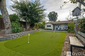 Oceanside house for rent - A backyard with a putting green and a house in the background.