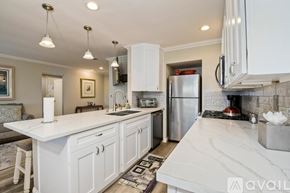 Oceanside house for rent - A kitchen with white cabinets and a marble countertop.